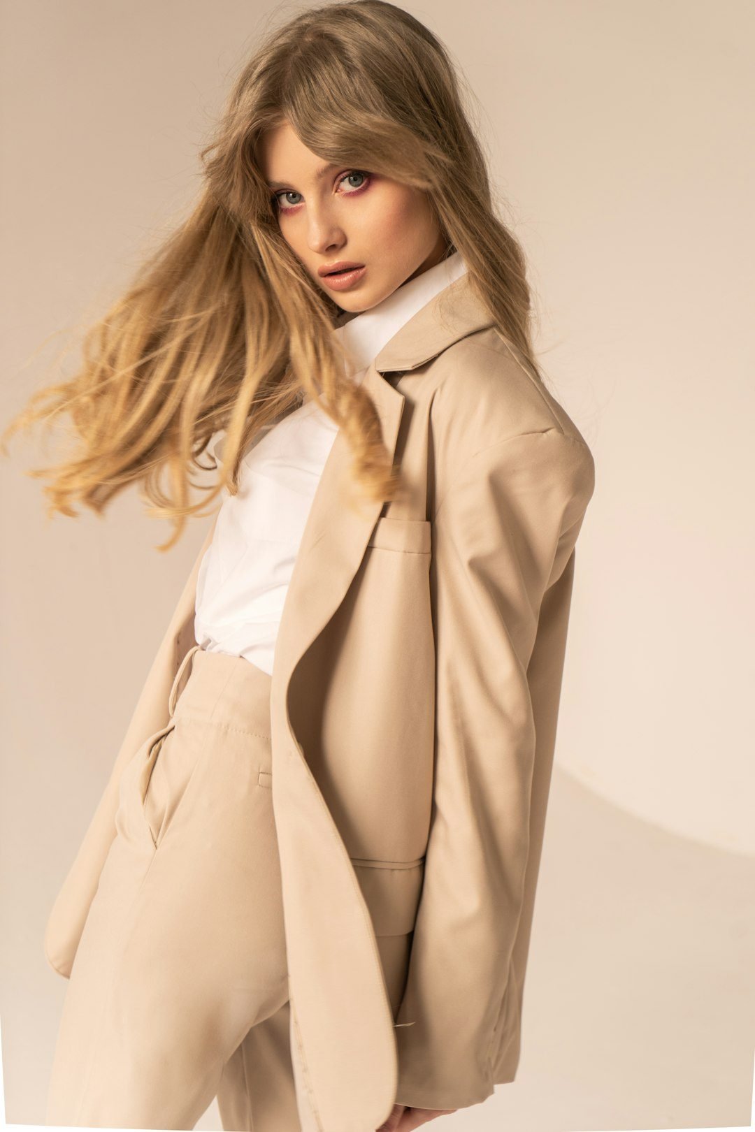 A model in a beige coat in a studio